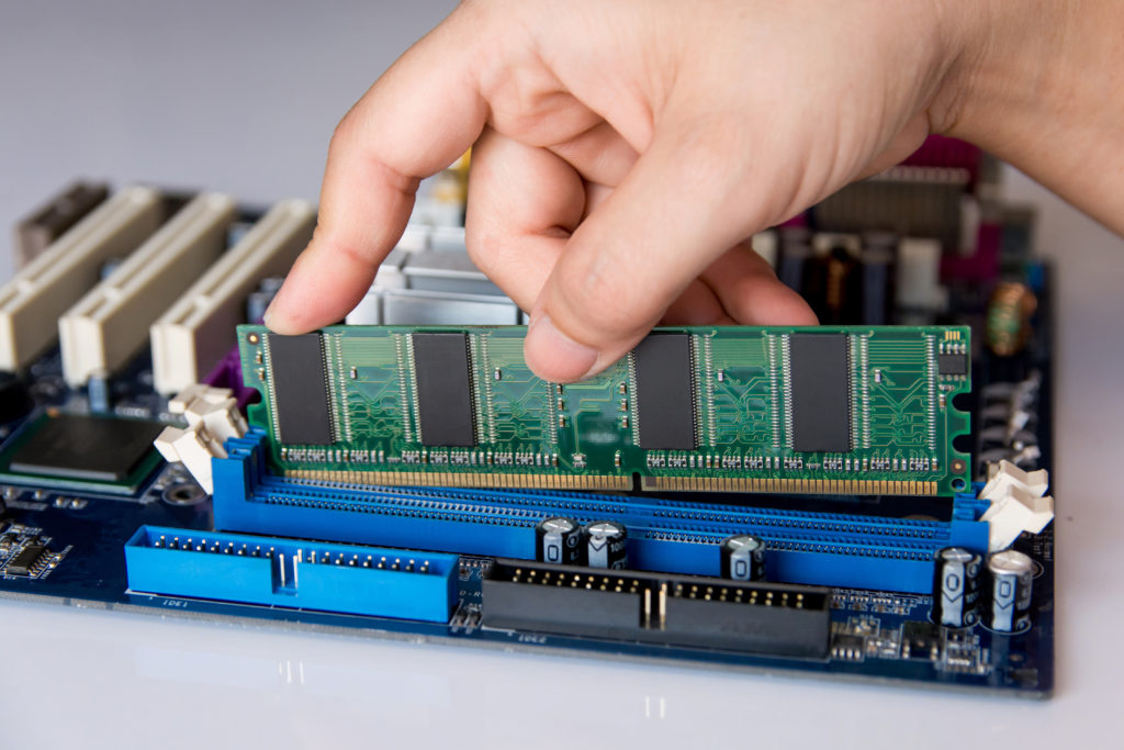 Technician installing RAM stick (random access memory) into the motherboard.