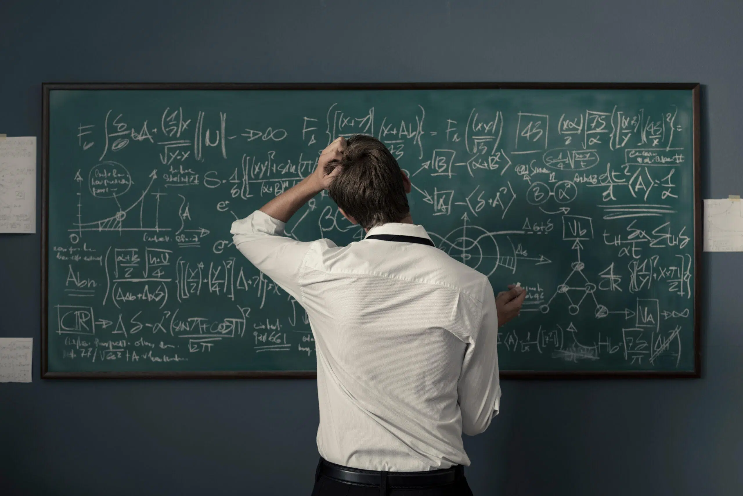 Mathematician solving problems and writing formulas on the chalkboard
