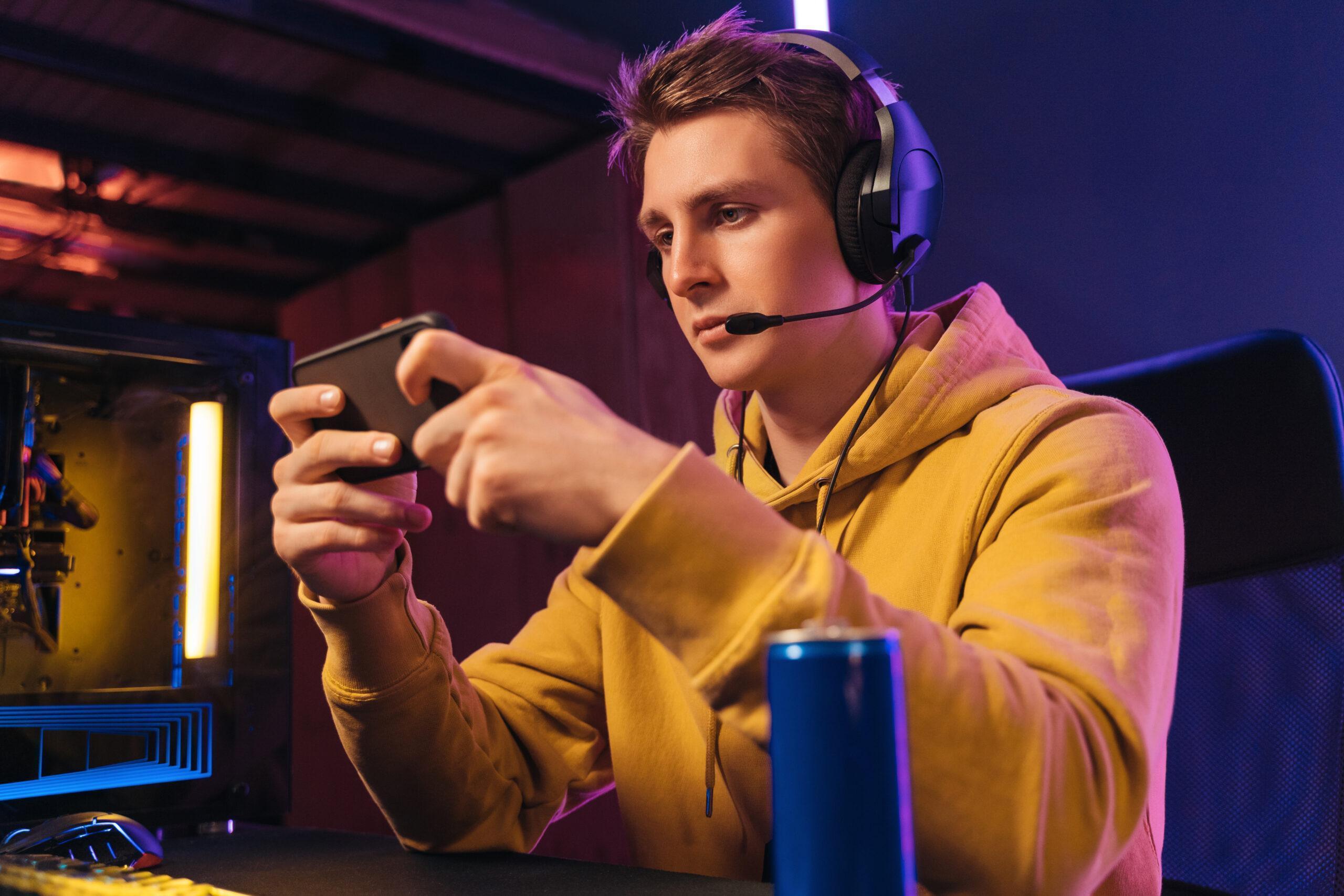 Young pro gamer playing in online mobile video games in neon colored room