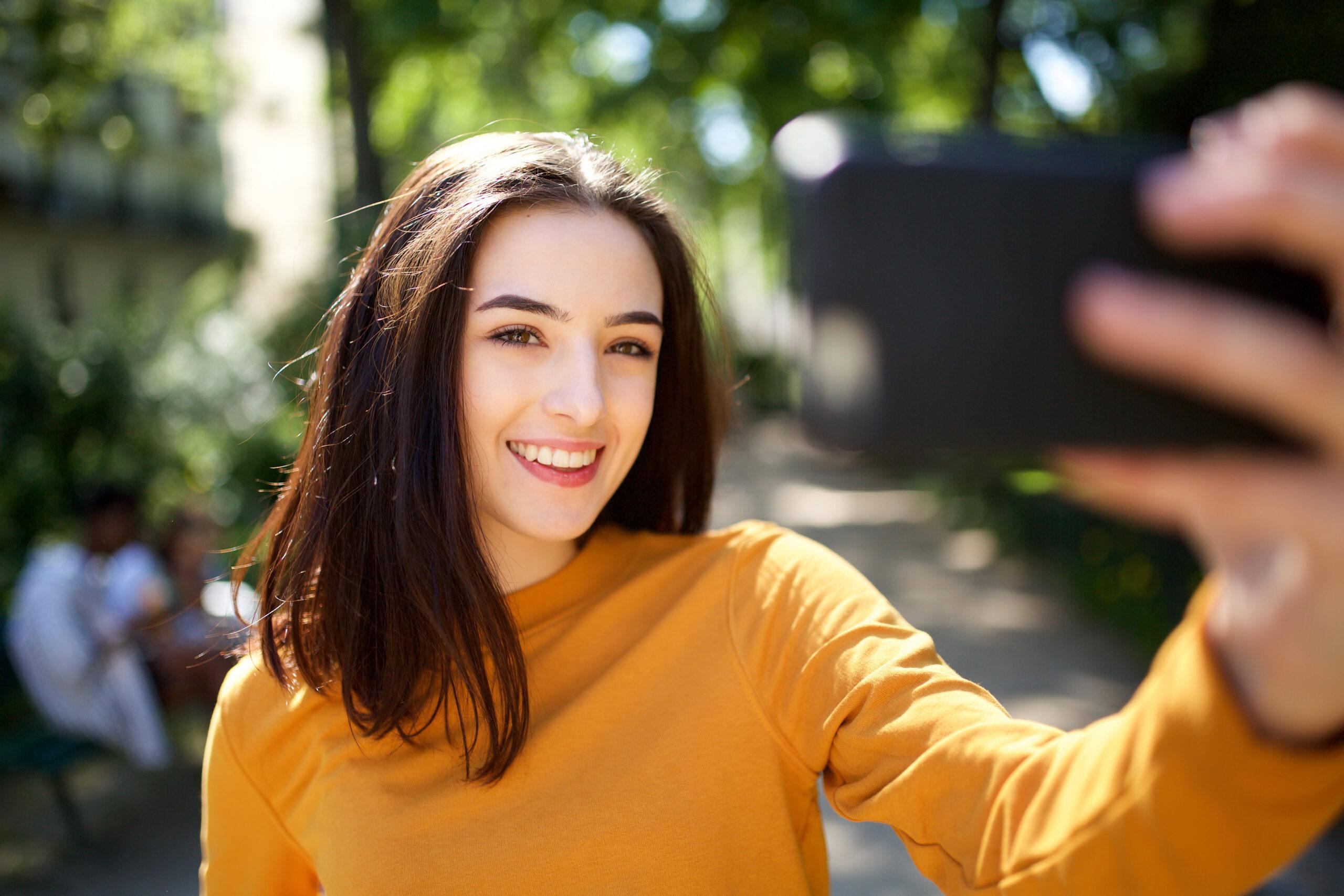 Pretty brunette taking a selfie asking herself "why are my selfies backwards?"