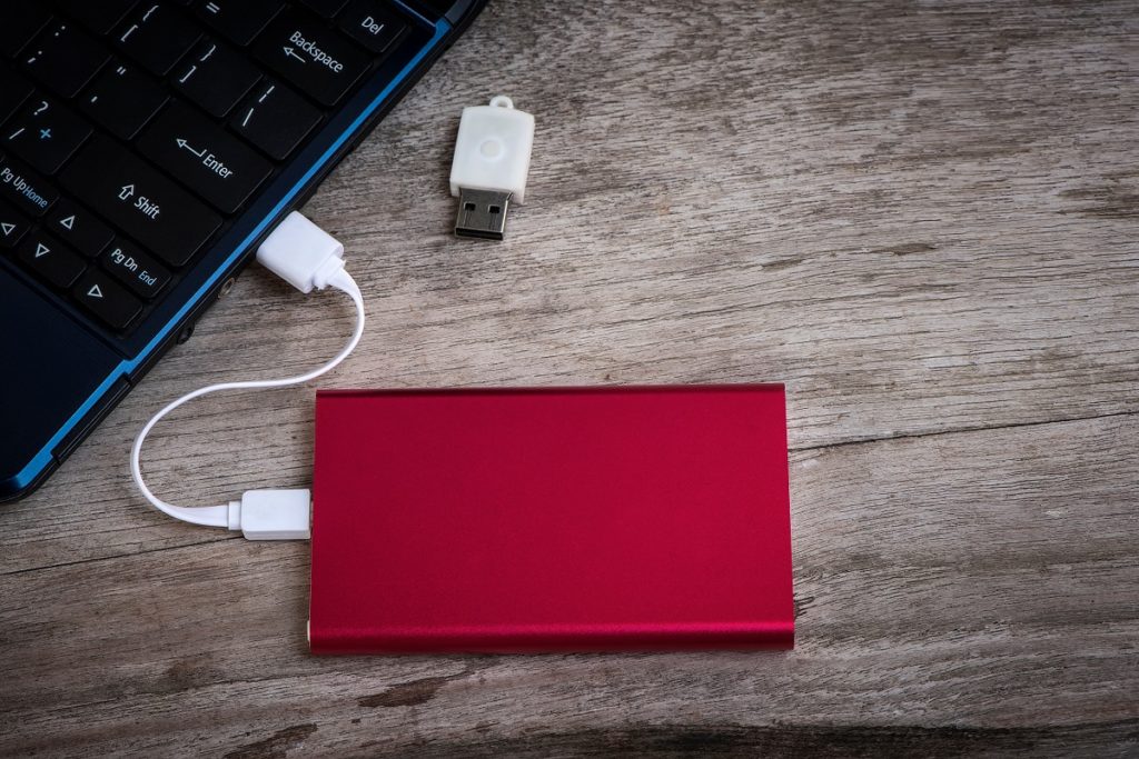 Red external hard drive (HDD) connected to a laptop.