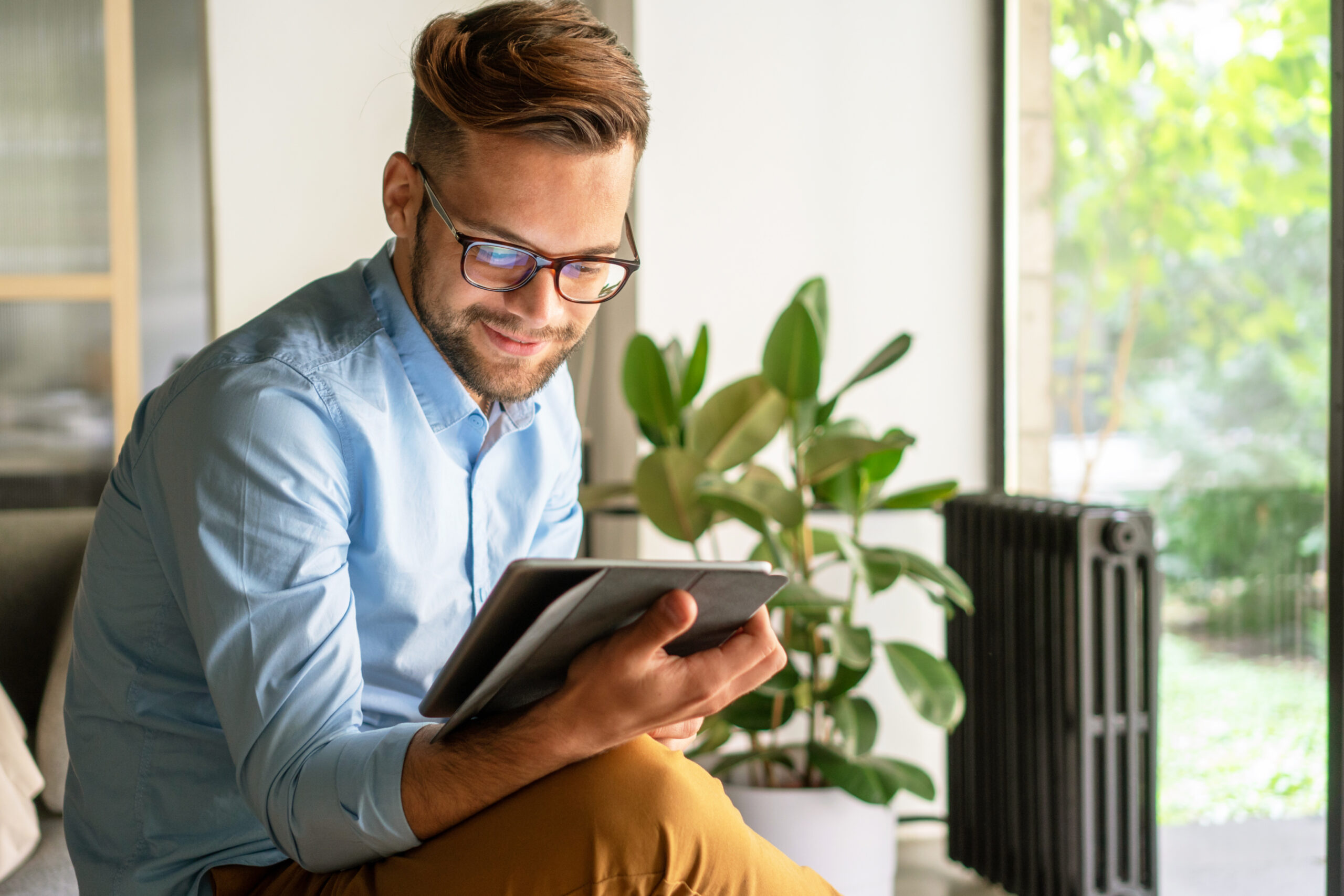 guy with glasses smiling while using a digital tablet