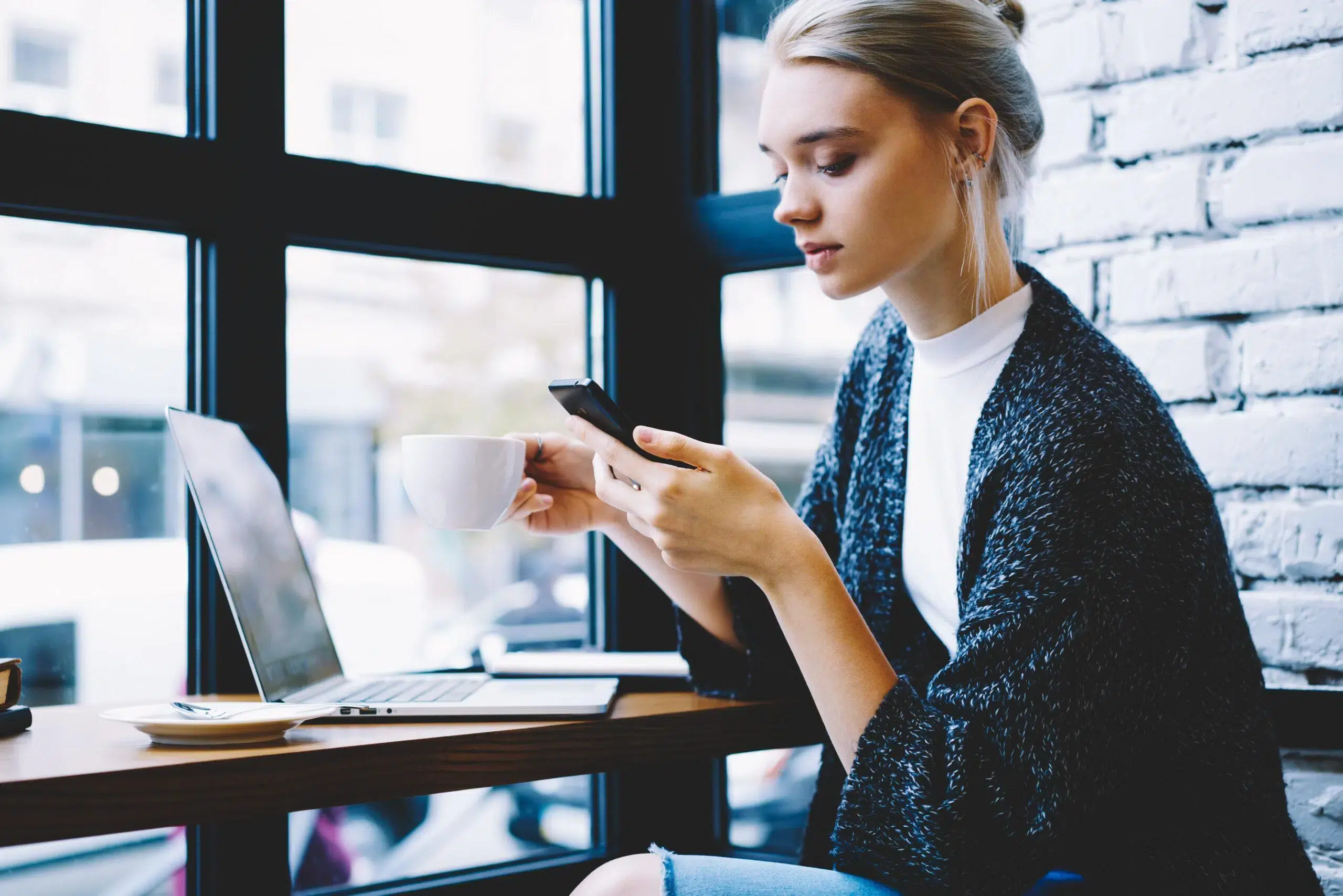Thoughtful blonde female working on how to unfollow someone on Instagram so that they will not know.