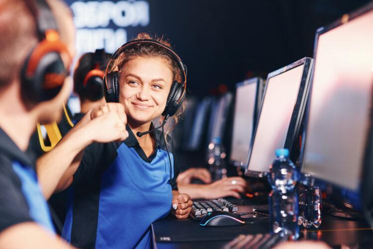 Two young happy professional cyber sport gamers giving fist bump and celebrating success while participating in eSports tournament