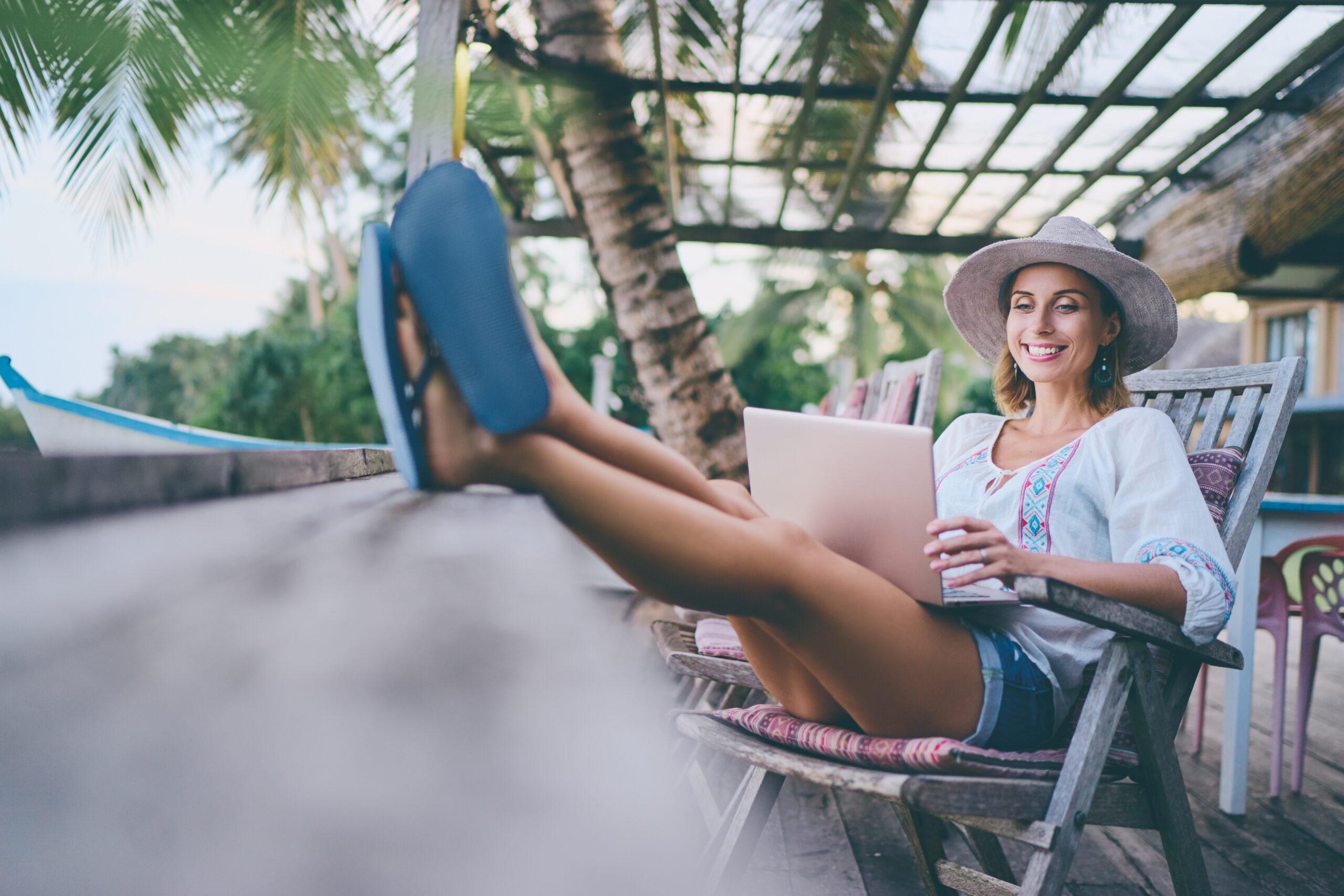 Woman working on her laptop while on vacation in a tropical country