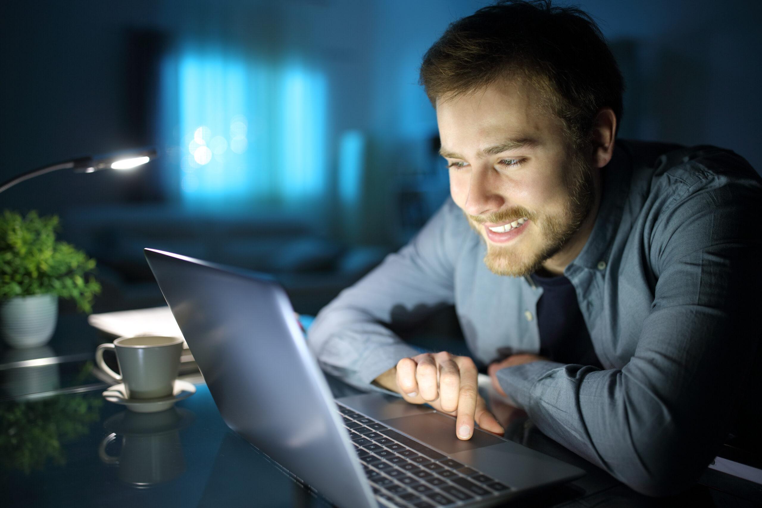 Happy man using laptop in the night at home