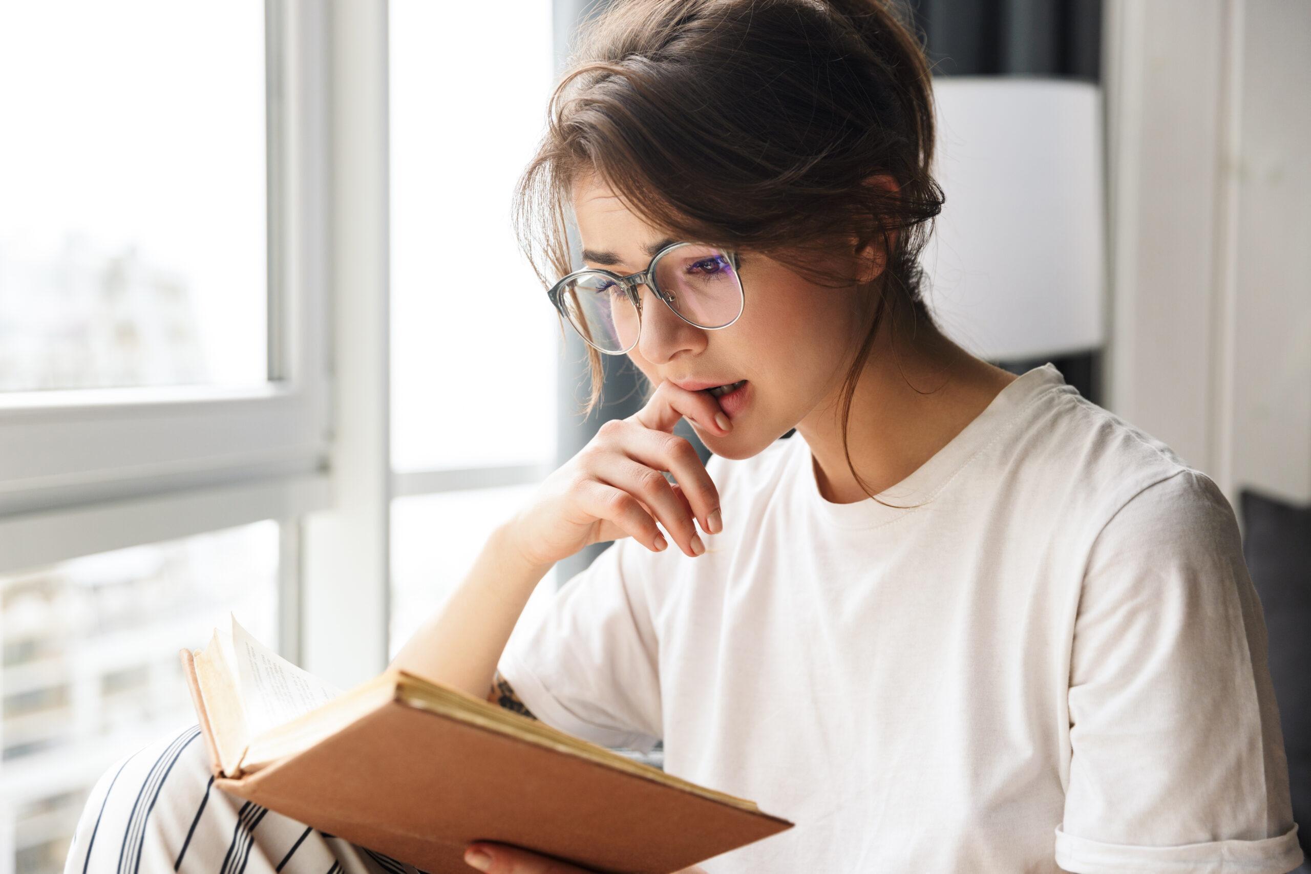 Young woman in eyewear visibly moved by what she is reading