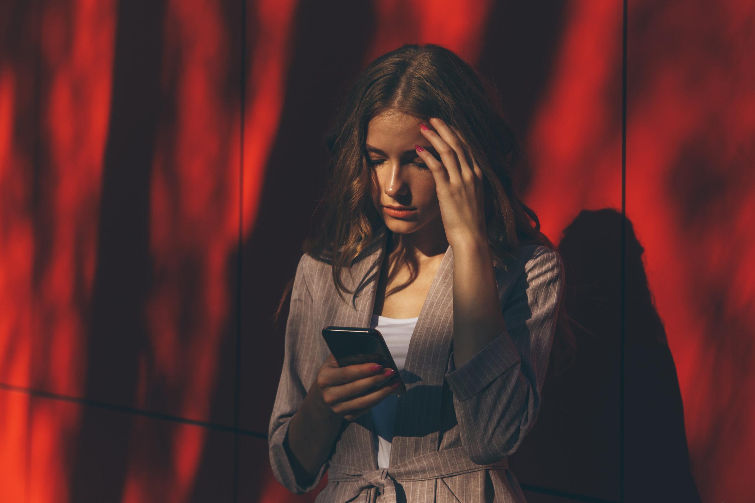 Unhappy young woman using smartphone portrait. Sad girl reading bad news or texting with mobile phone