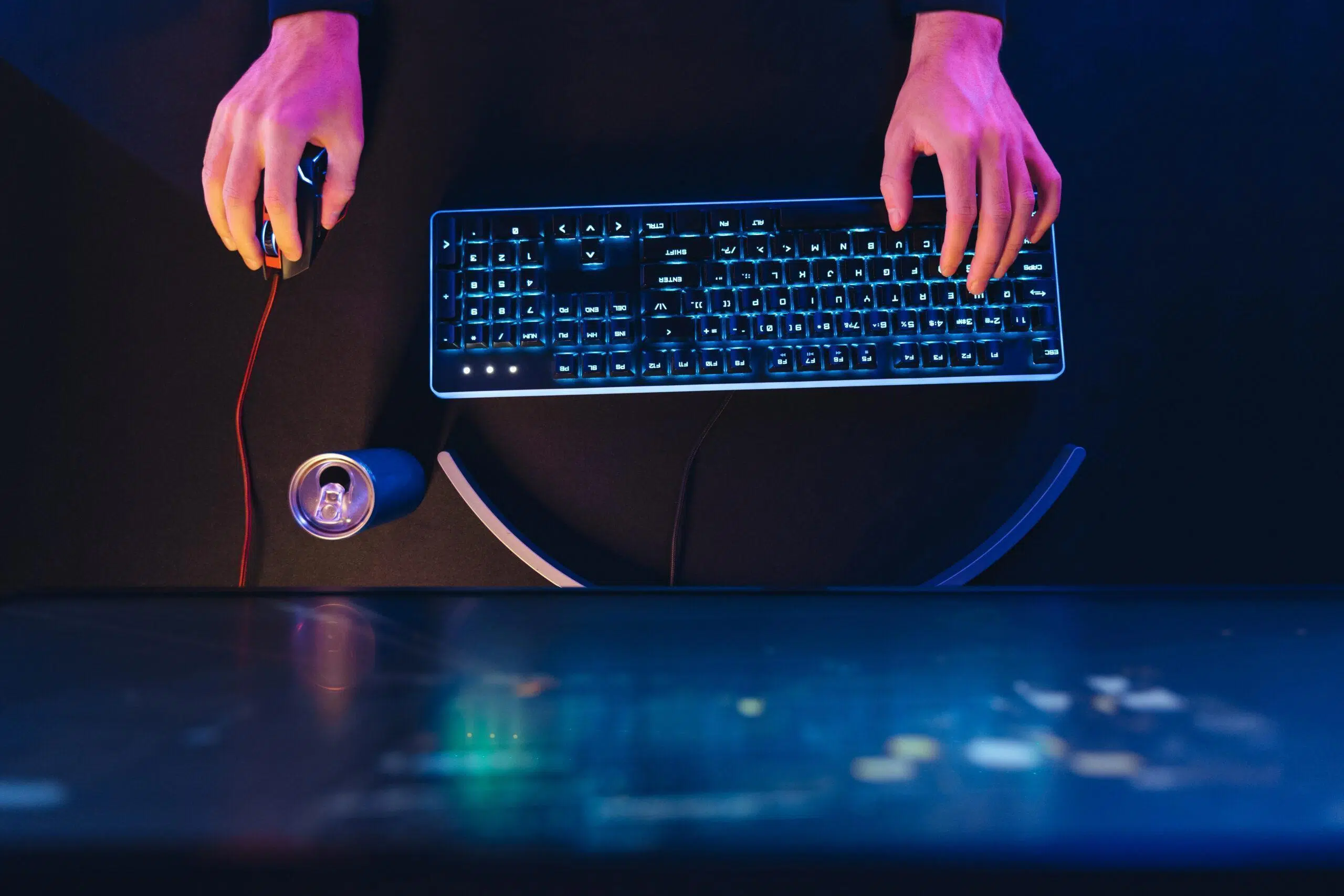 Pro gamer's hands on professional gaming keyboard and computer mouse in neon color
