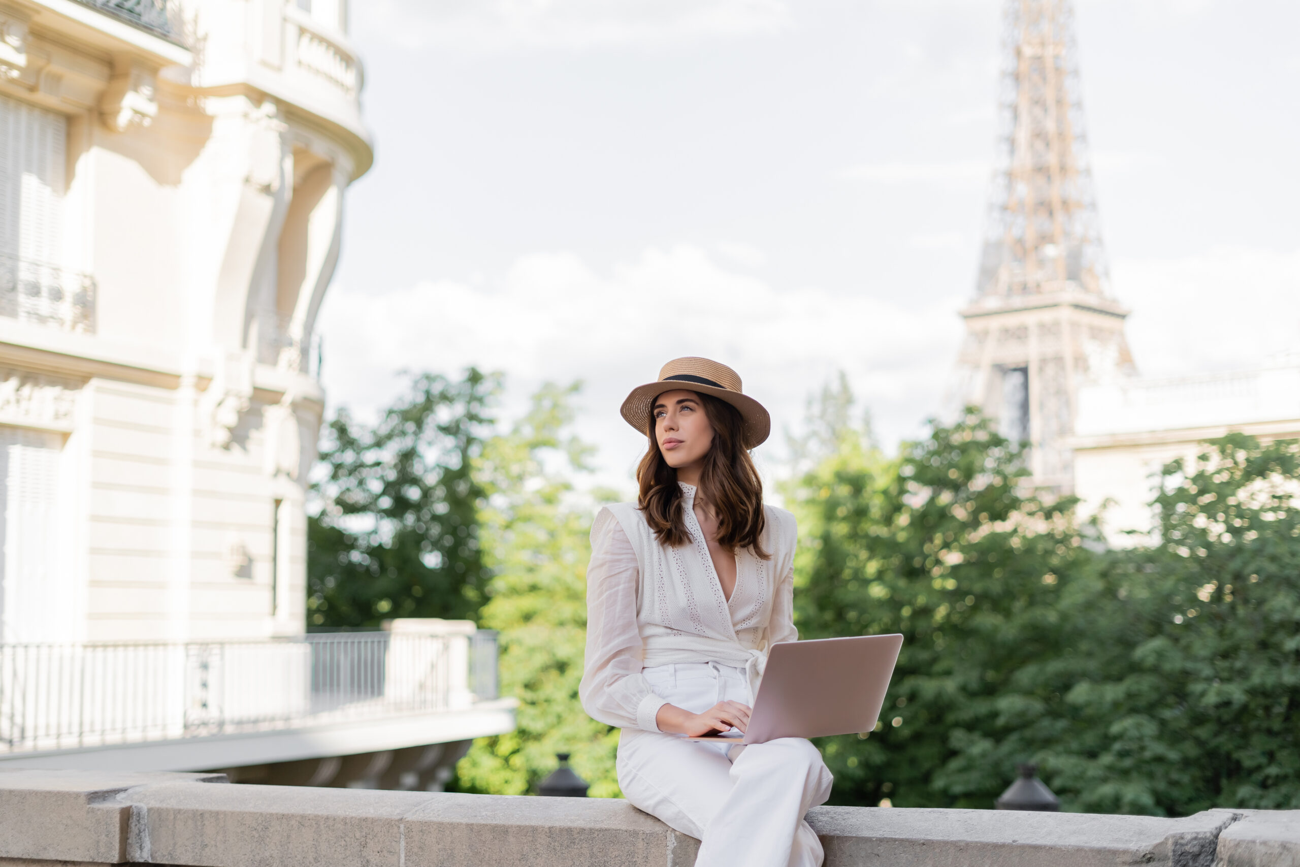 stylish professional woman working on a laptop outdoor with eiffel tower in the background