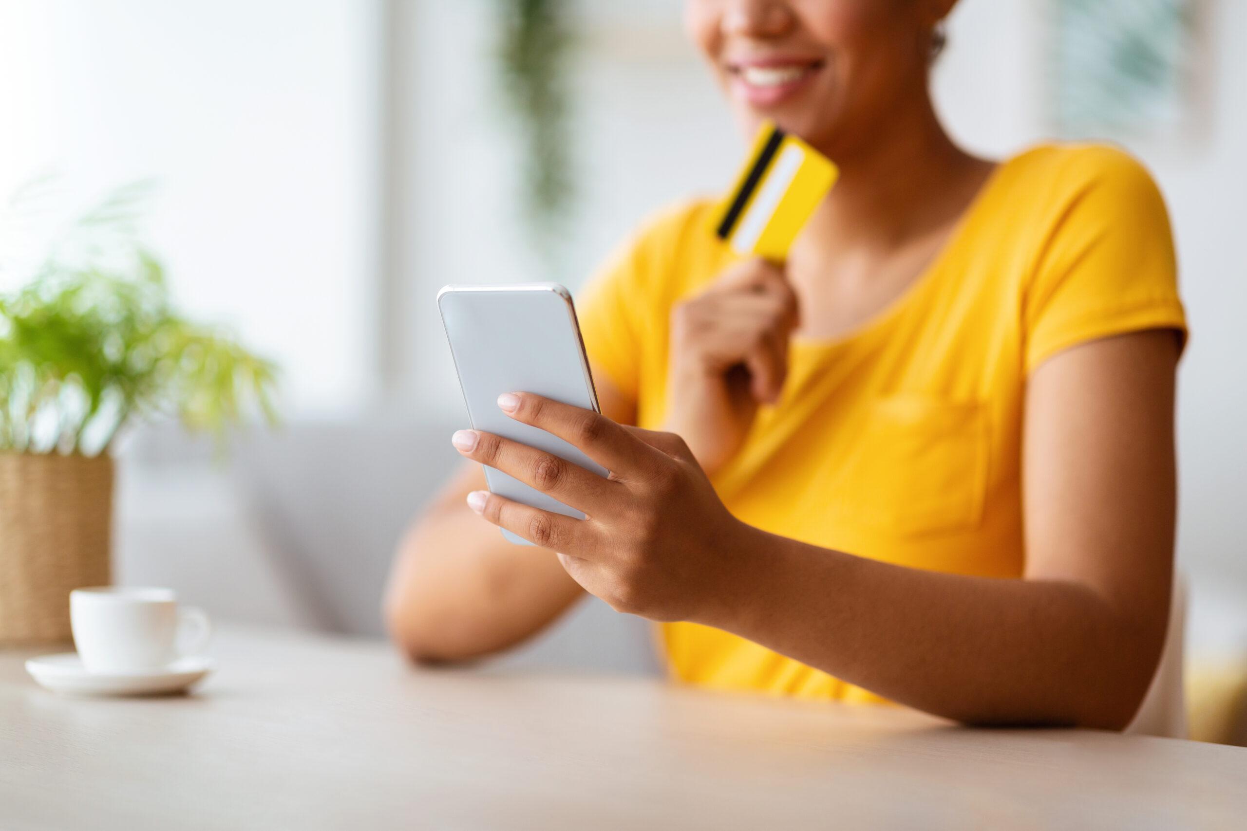 African-American lady using phone and credit card at home