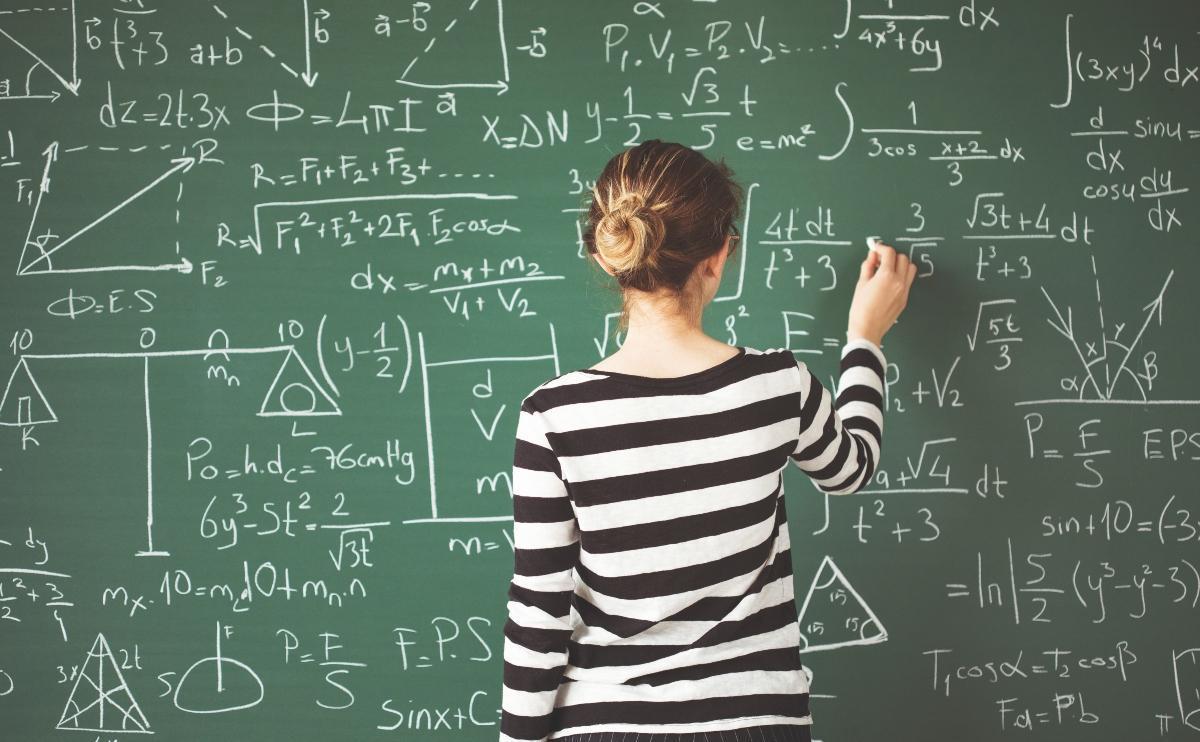 Woman solving complicated math problems on the black board