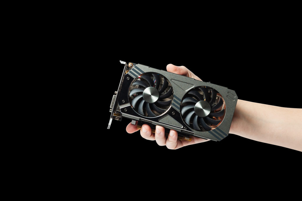 Man holding a graphic gpu video adapter isolated on a black background.
