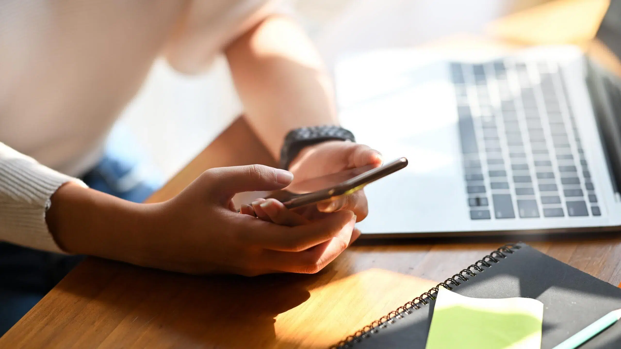 Close-up female holding her smartphone on workspace