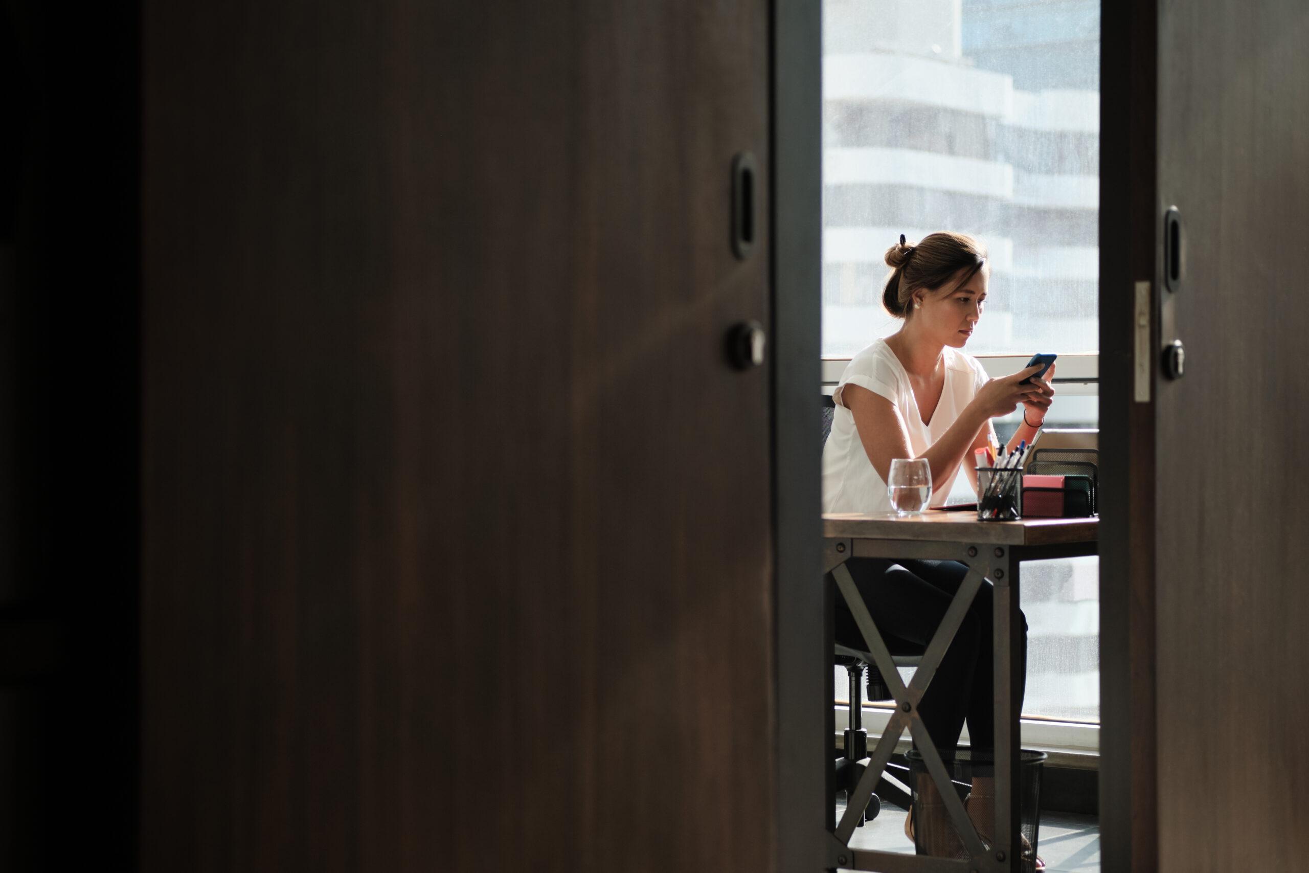 Woman Working In Corporate Office Sending Email With Phone