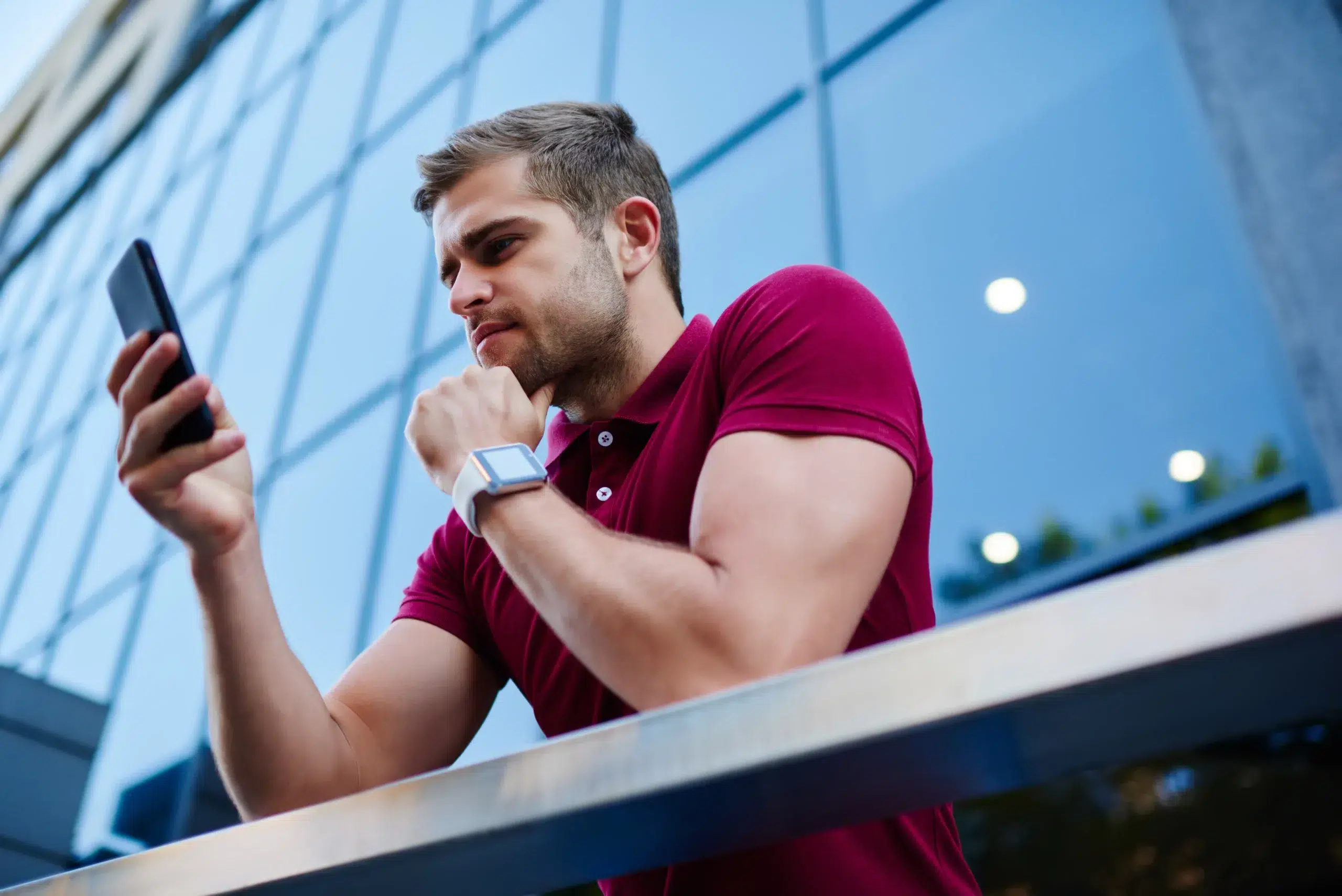 Handsome man browsing mobile smartphone near big building