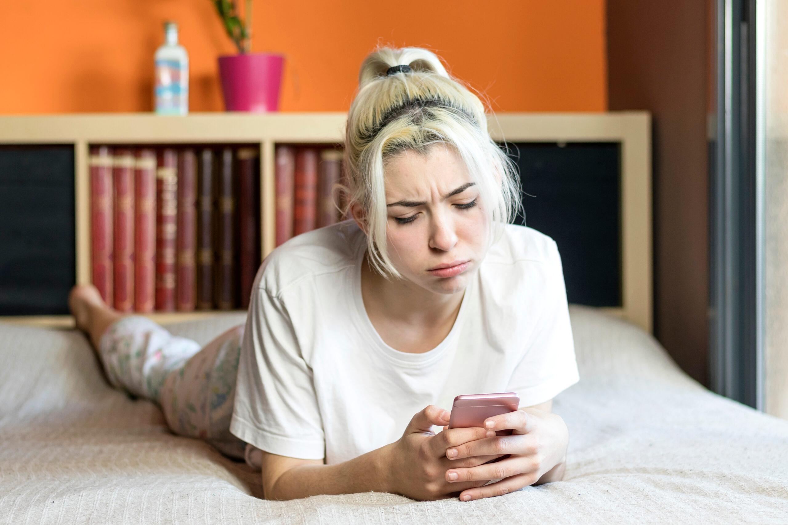 Sad  blond girl reading message on the phone