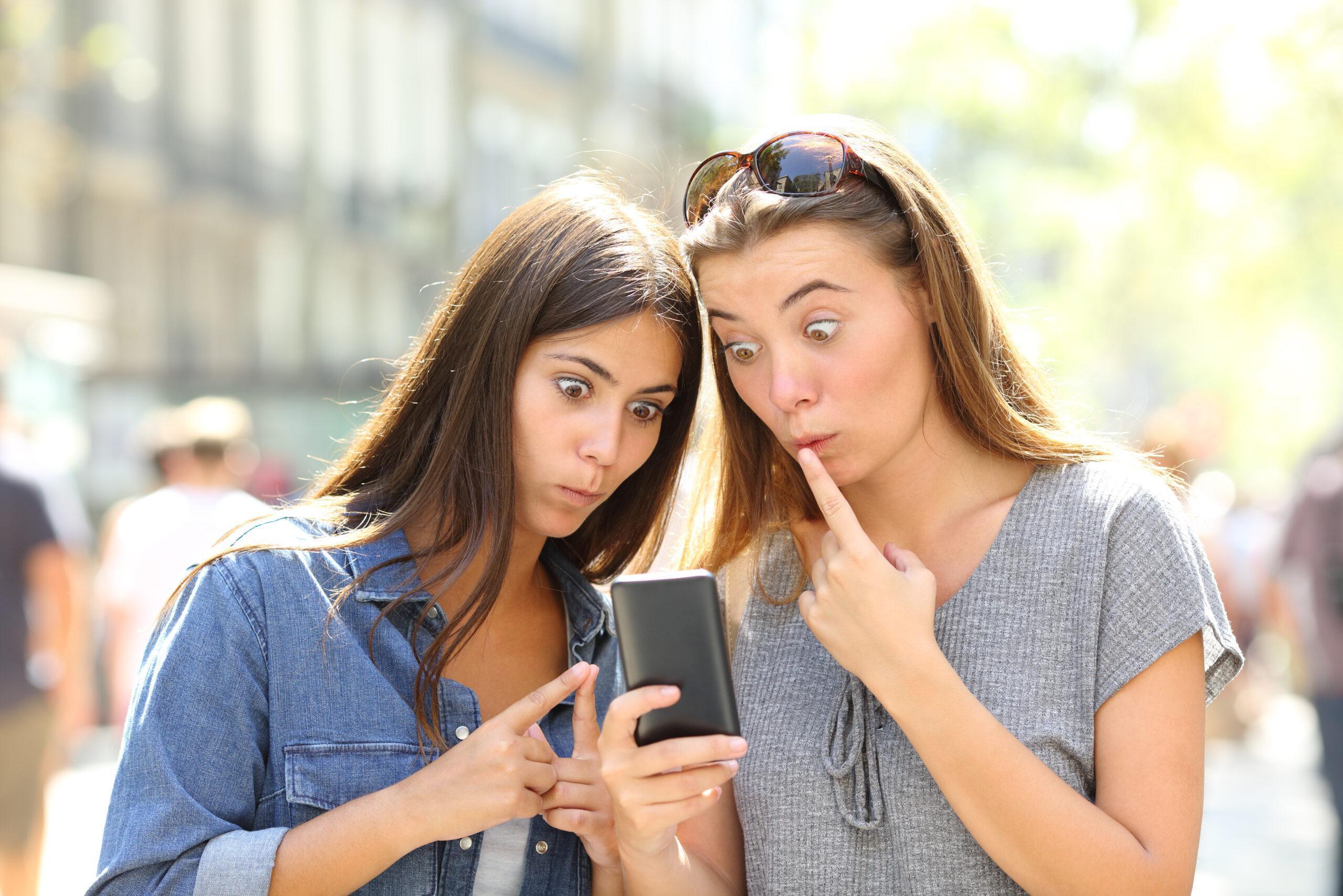 Two friends with surprised faces looking at the phone