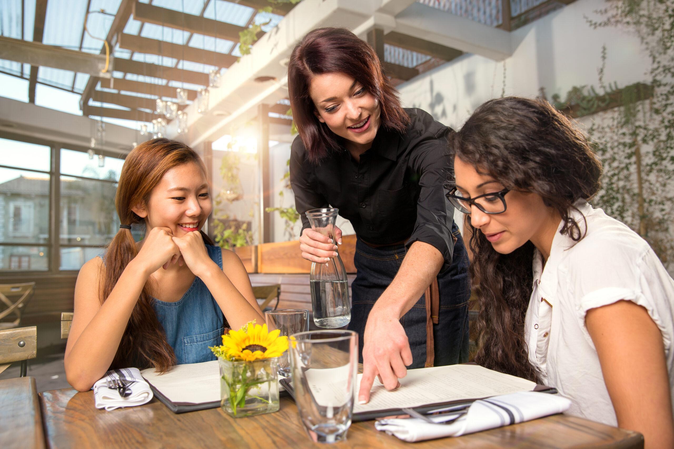 Server waiter pointing to menu for patron customer helping at ta