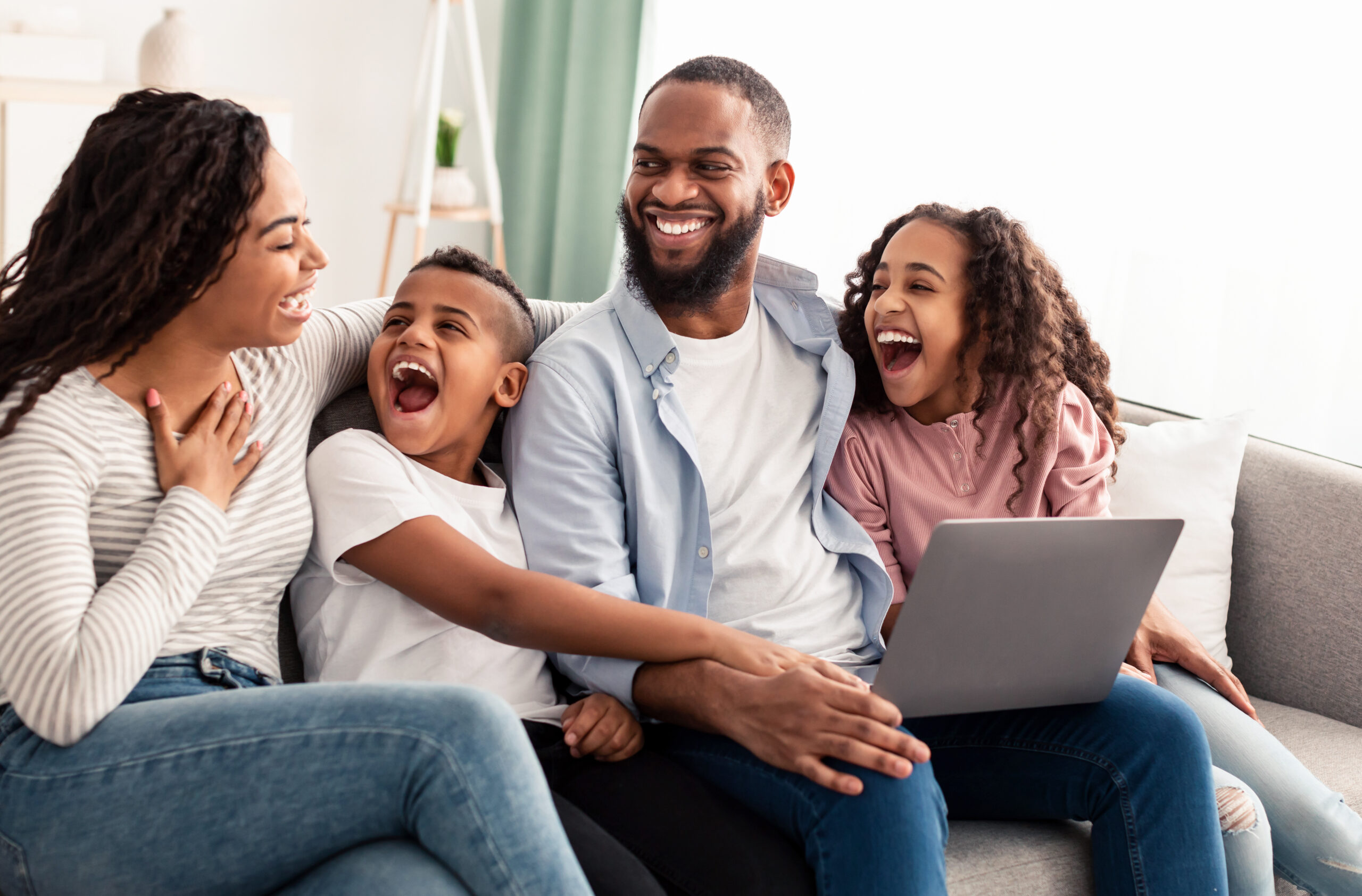 Laughing Africans American family using laptop in living room