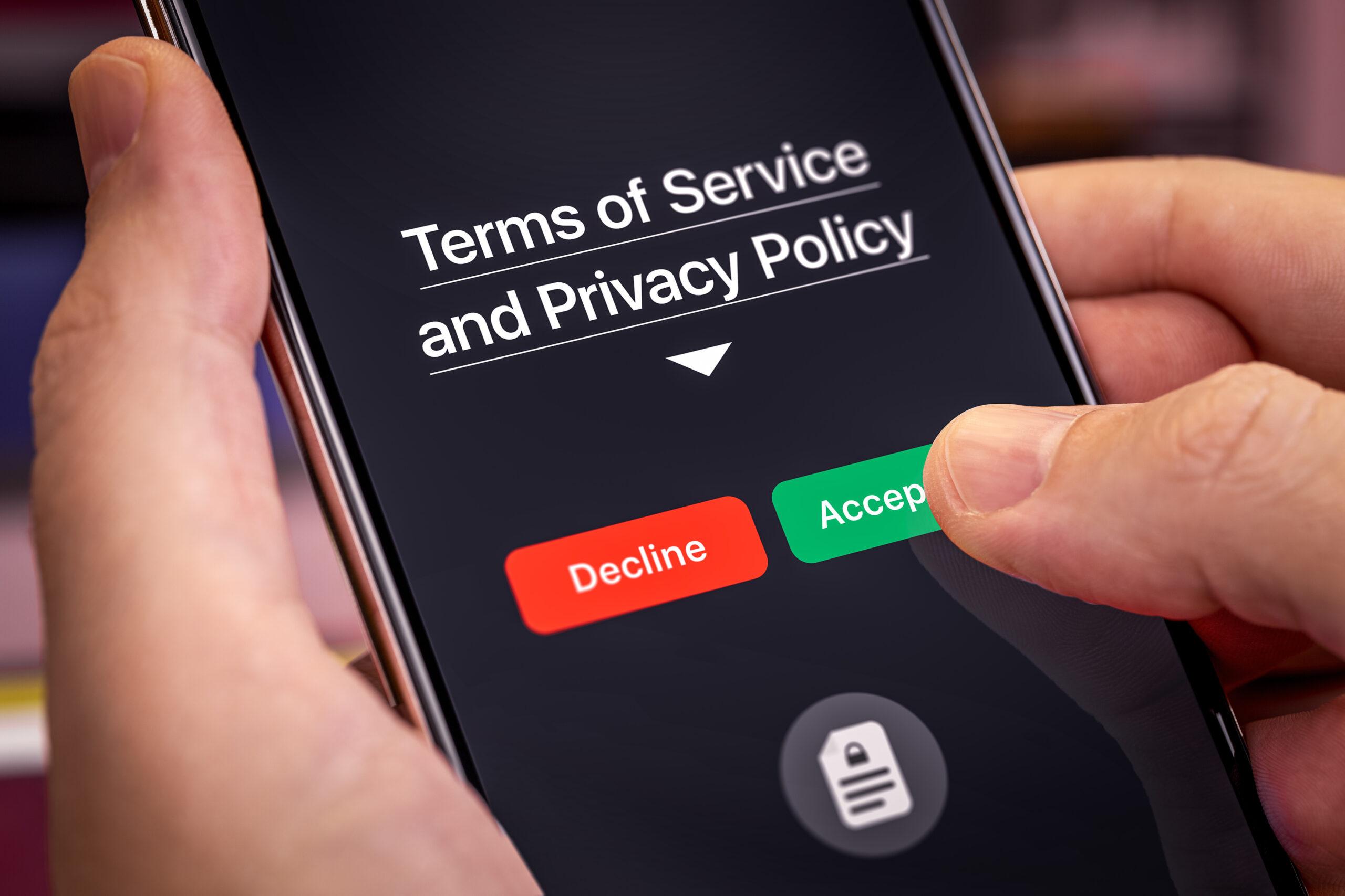 Smartphone user agrees to accept Terms of Service and Privacy Policy mobile app. Finger touches the Accept button. Dark app interface with Accept and Decline buttons.