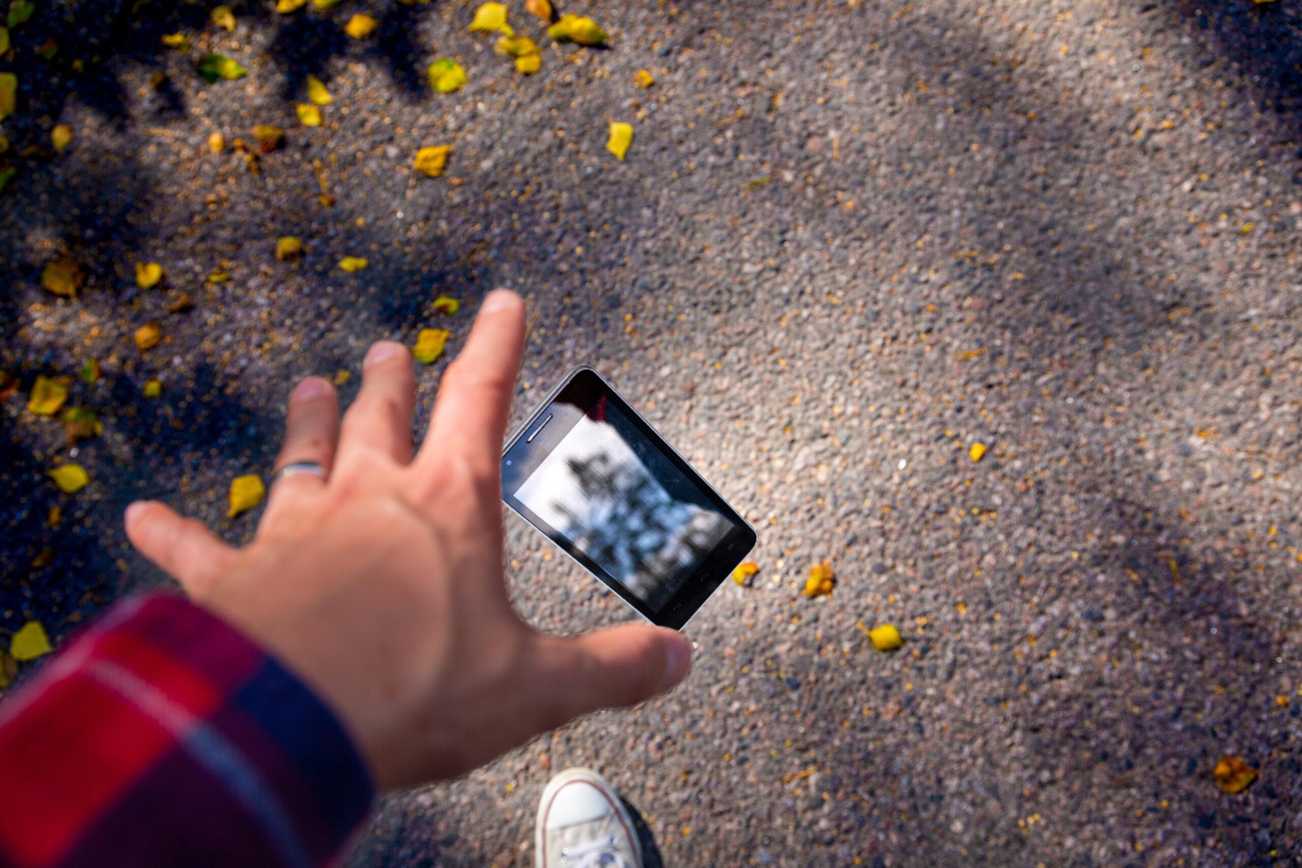 Hand reaching out to grab a phone that fell 