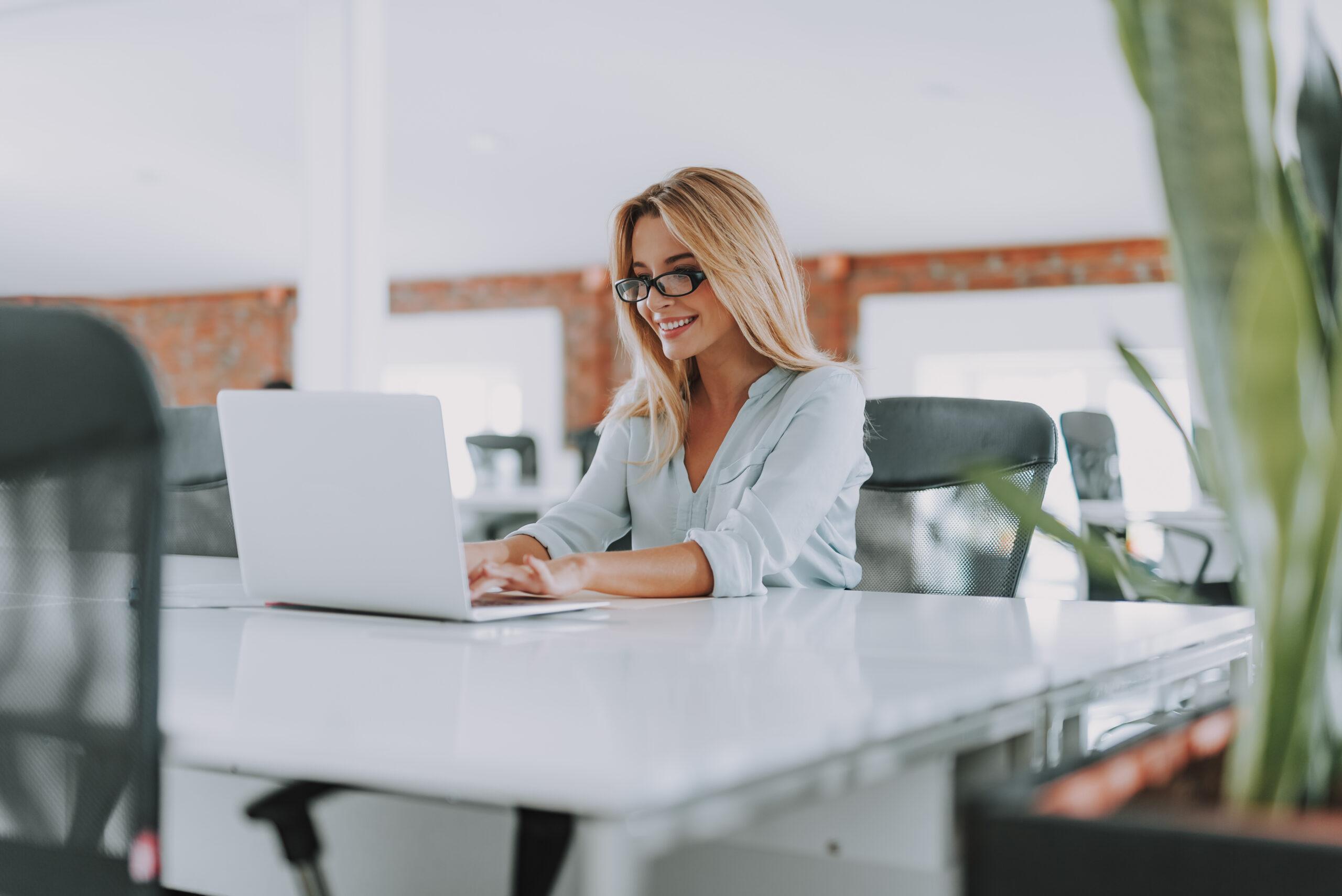 Enthusiastic woman smiling and working on her laptop