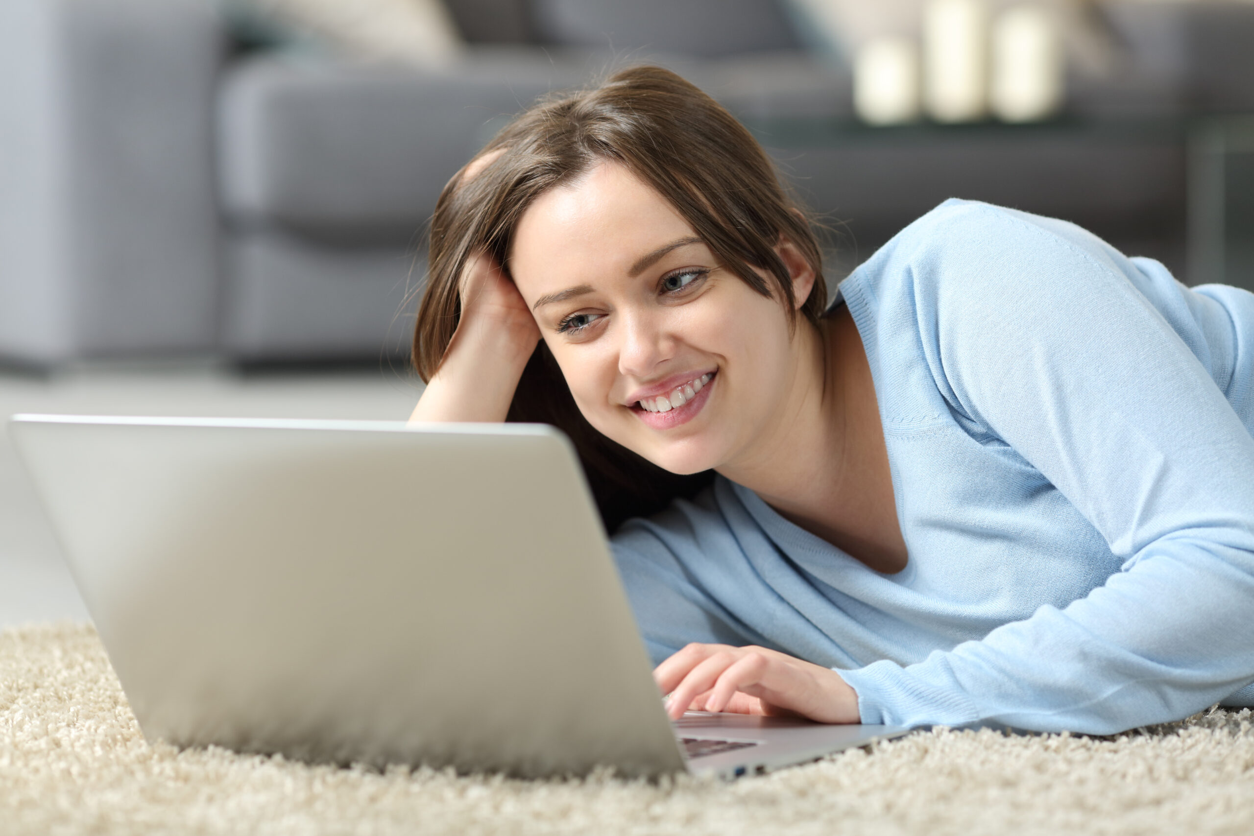 Happy teen using laptop on the floor at home