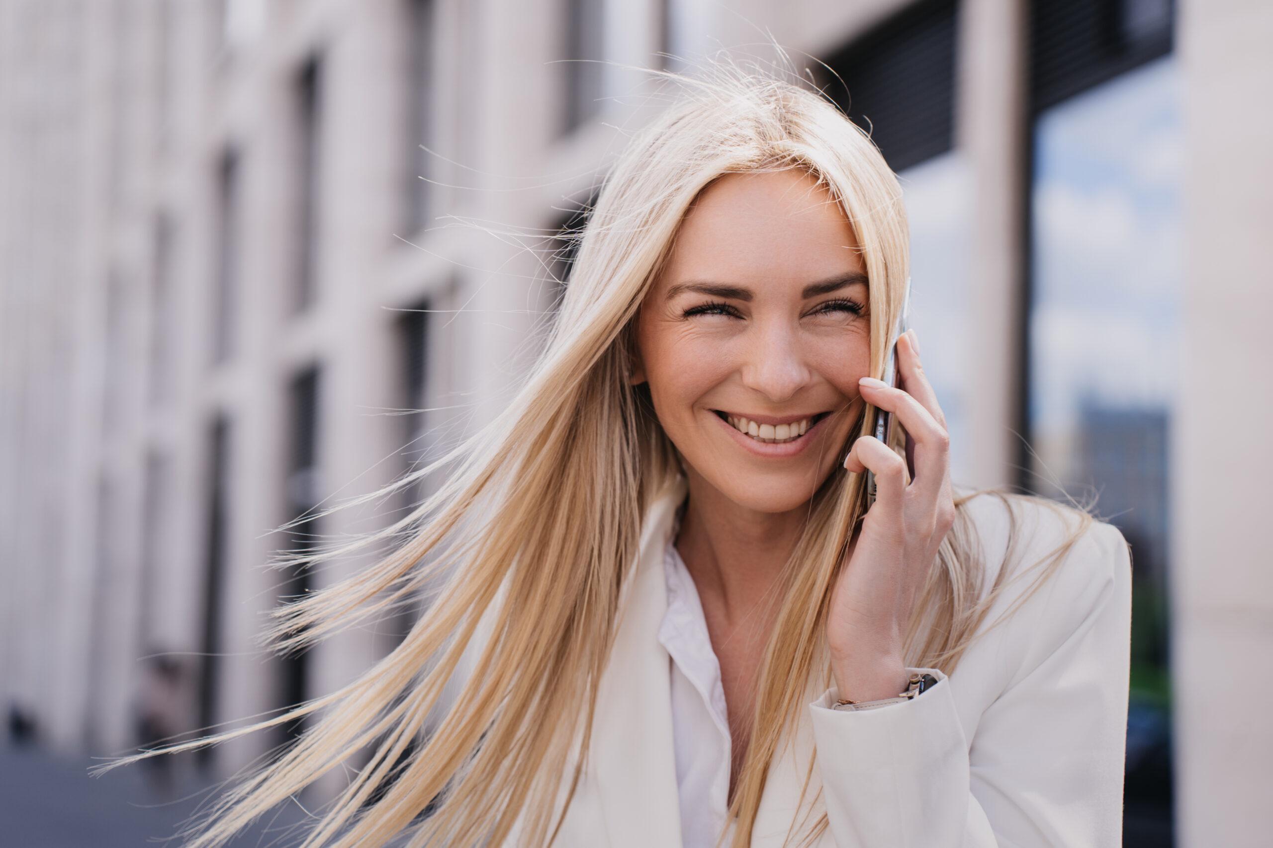 Blonde woman talking on the phone outside