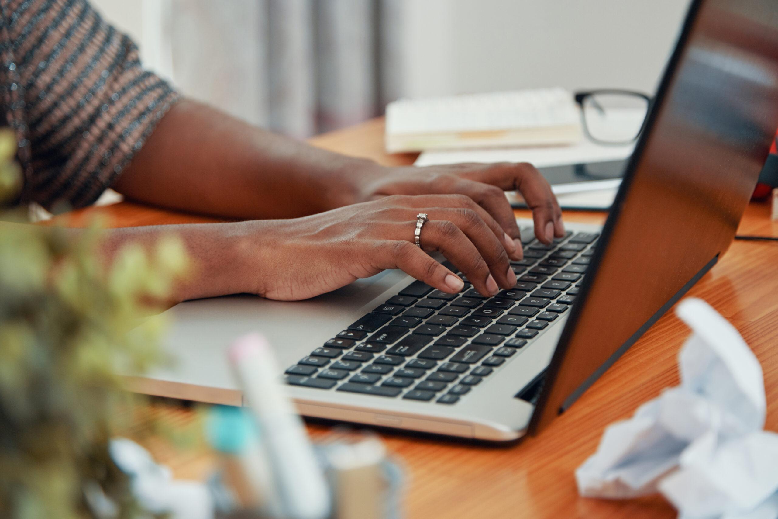 Crop black woman typing on laptop