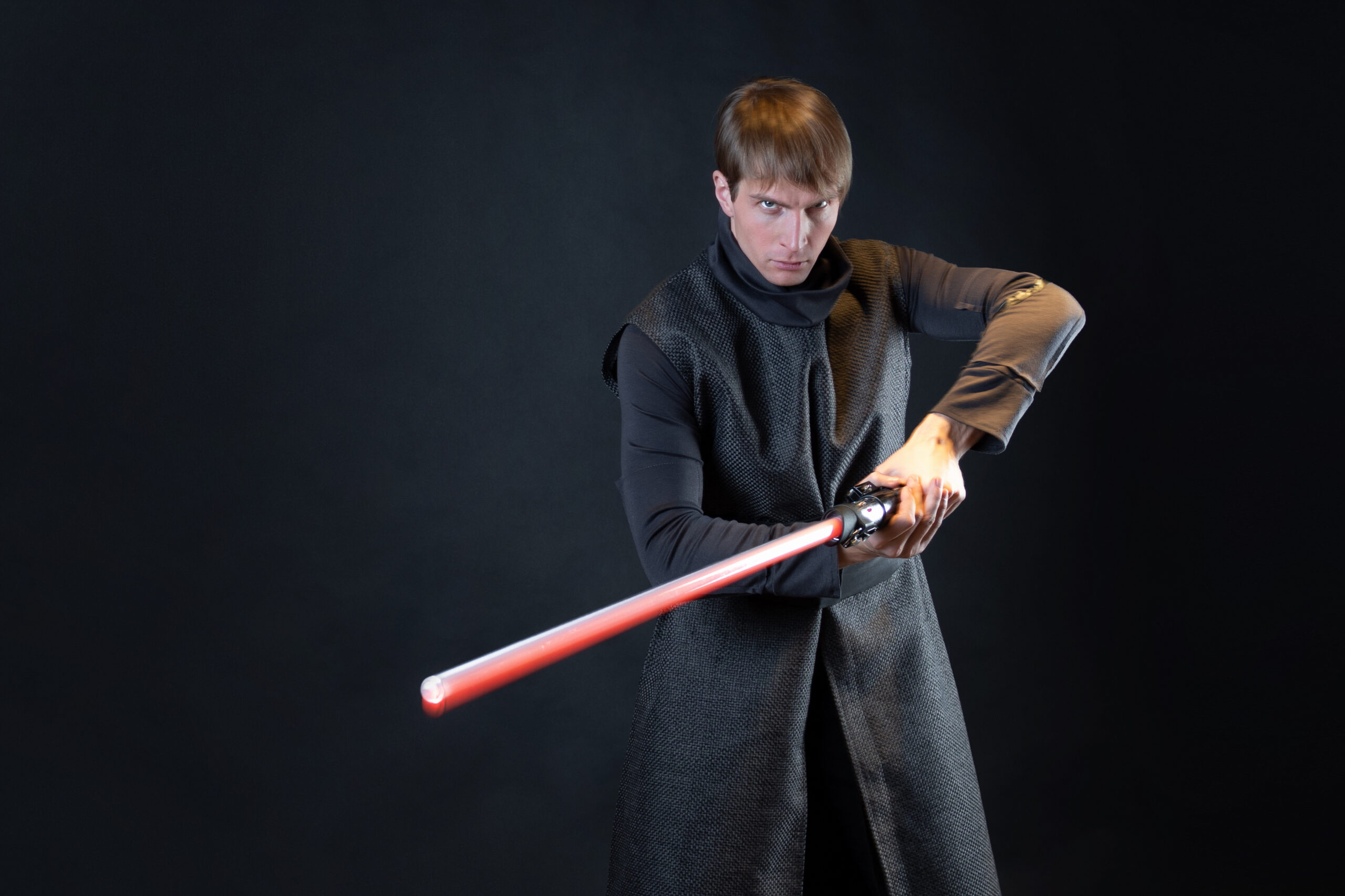 A Star Wars fan dressed as a villain and holding a red lightsaber