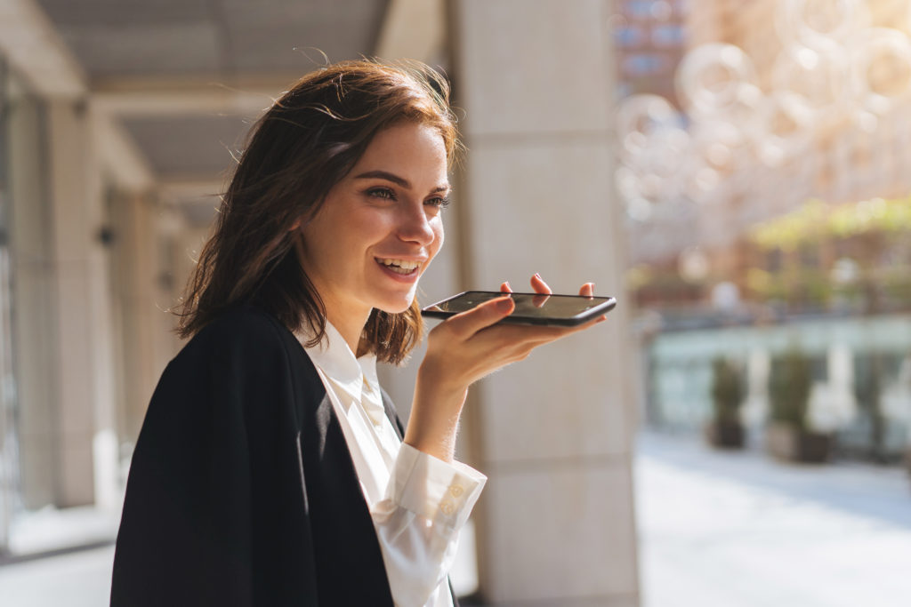 Young beautiful woman using smartphone voice messenger.