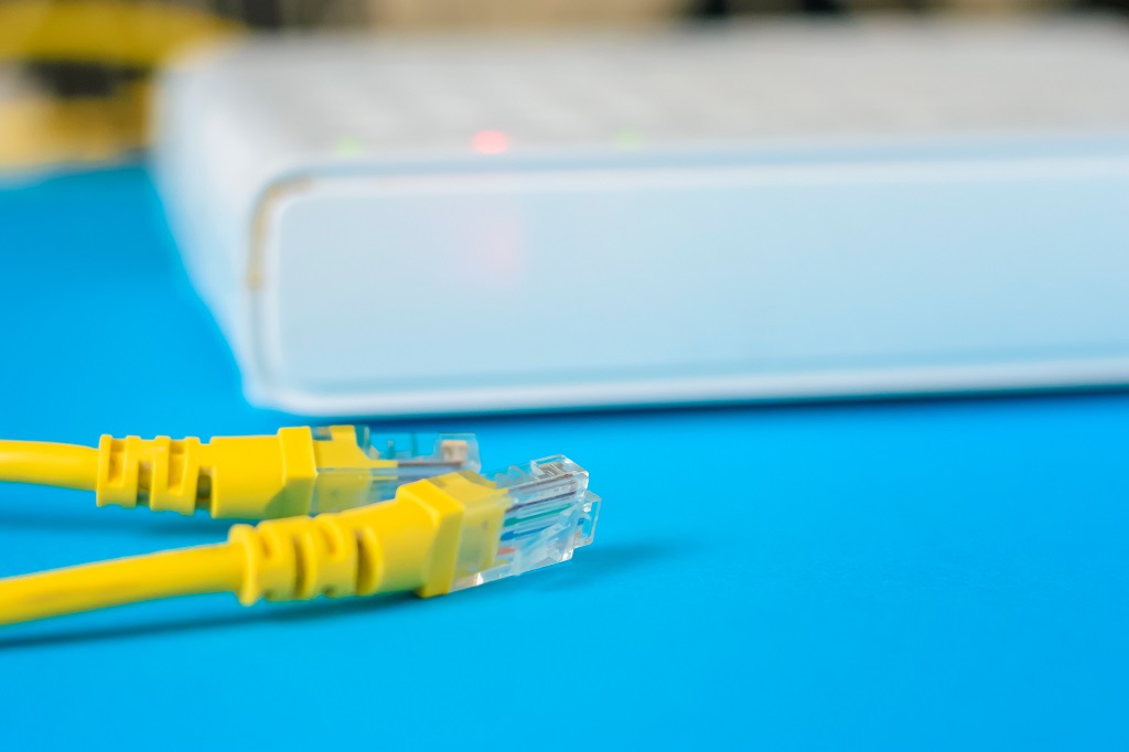 unplugged ethernet cable and internet router on a blue background.