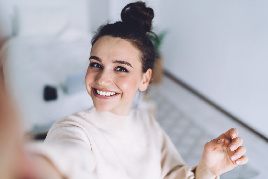 Attractive young woman taking a video of herself on her mobile phone.