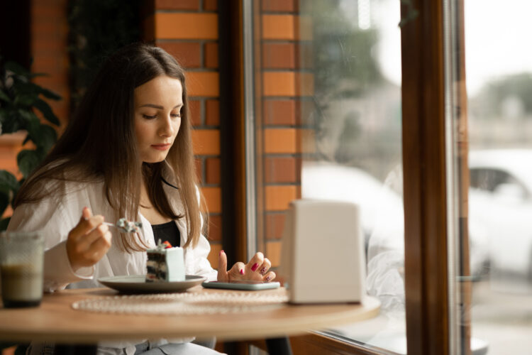 Charming serious woman checks her phone while relaxing at cafe
