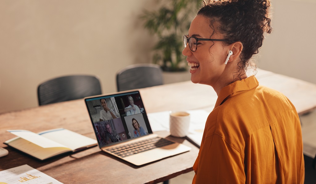 Woman laughing during a video call with team.