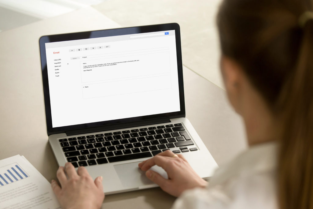 Businesswoman typing corporate e-mail using laptop at office desk