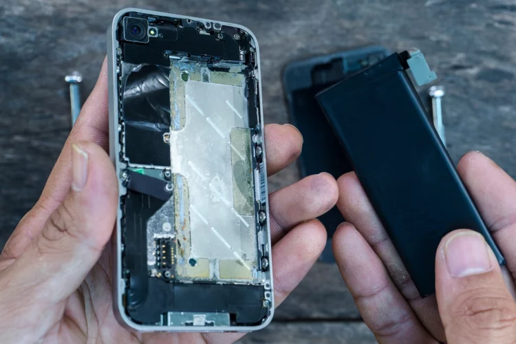 The technician holding a battery removed from the broken phone