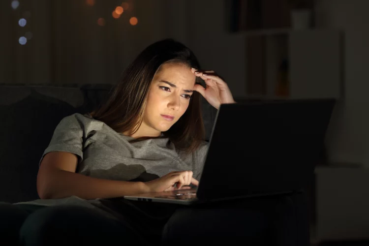 Worried woman using a laptop at night