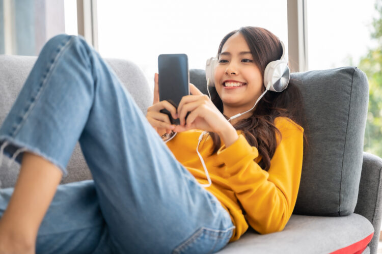 Beautiful asian young woman wearing headset and using mobile smartphone. 