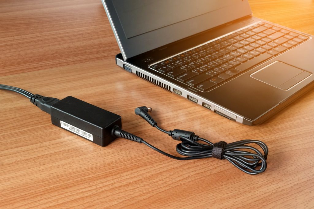 Adapter and power charger for laptop on a wooden table.