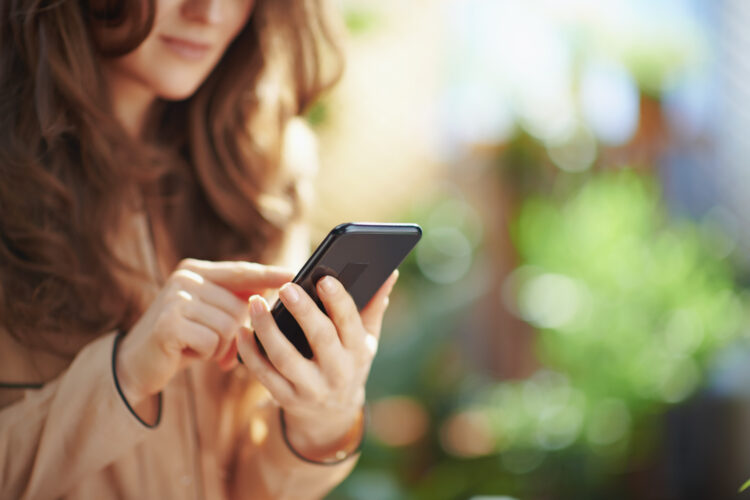 Elegant woman at home in sunny day using phone.