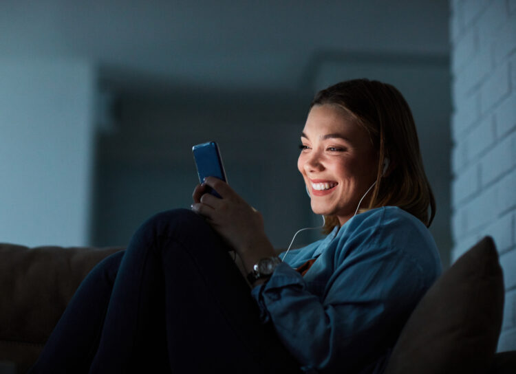 woman smiling while using smartphone at night at home.