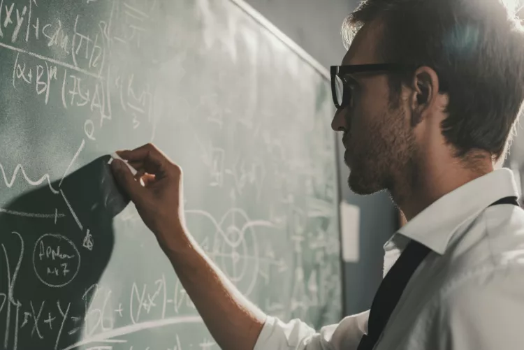 Young smart mathematician drawing on the chalkboard