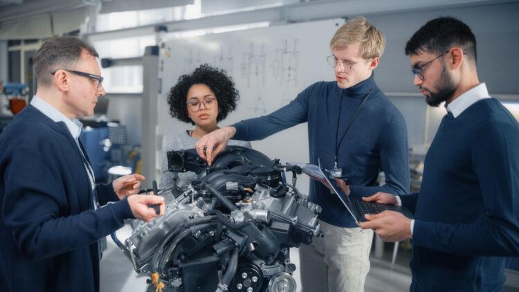 Male chief engineer explains to young specialists about components of the electric motor