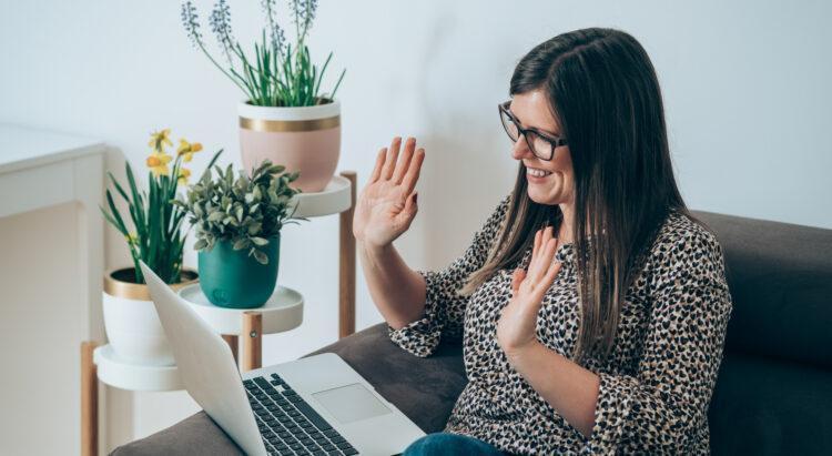 Smiling middle aged professional woman casually saying hello to a colleague on a video call
