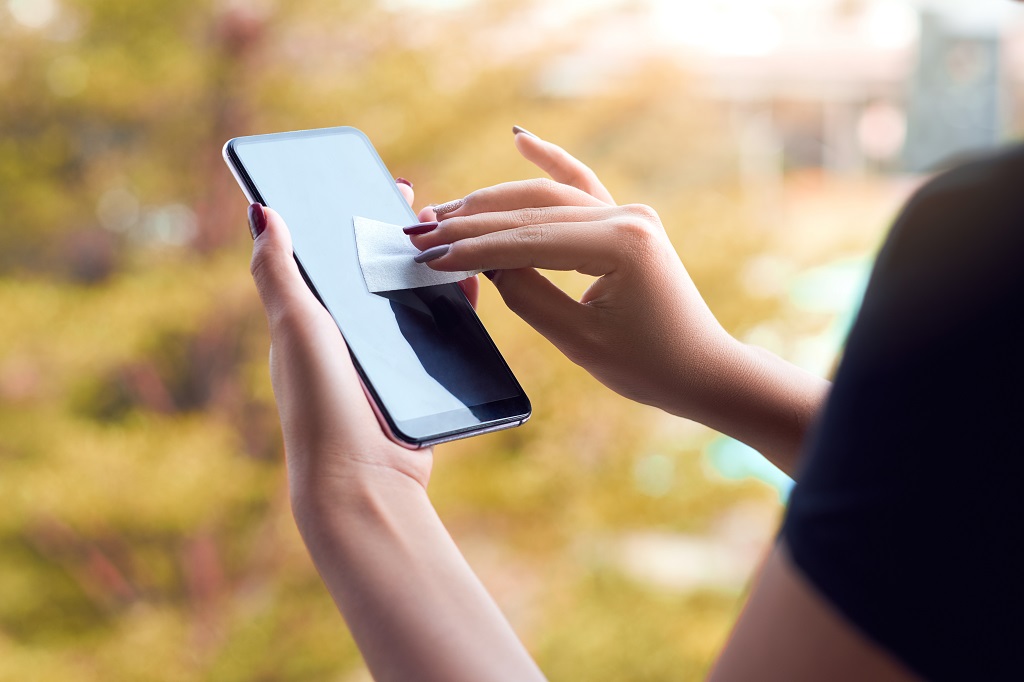 Cleaning mobile phone screen with disinfecting wet wipes.