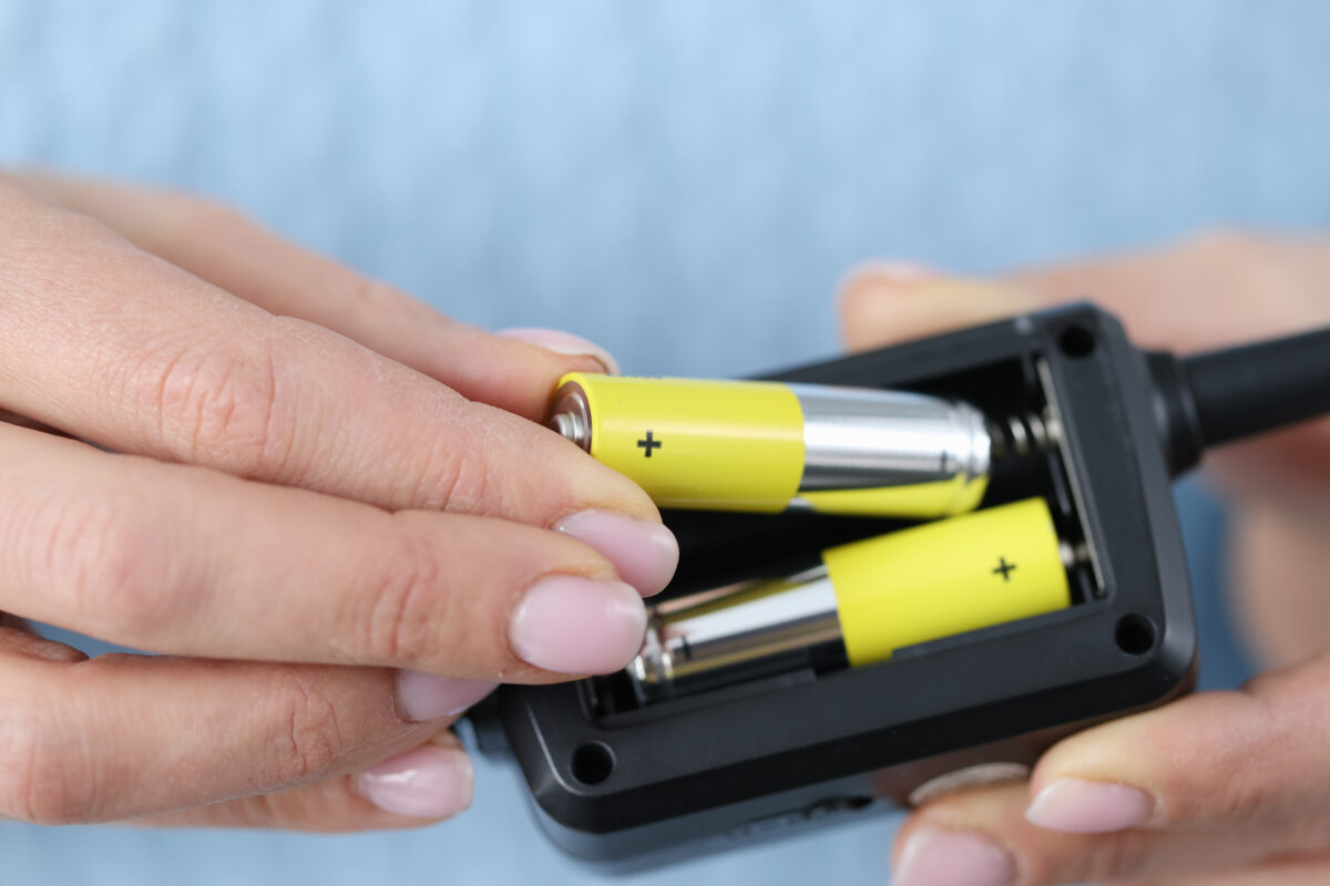 Female hands inserting alkaline batteries into remote.