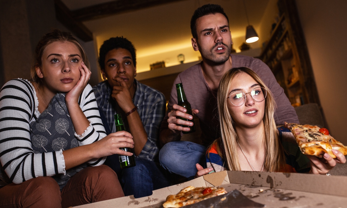 group of friends watching a movie over pizza and beer