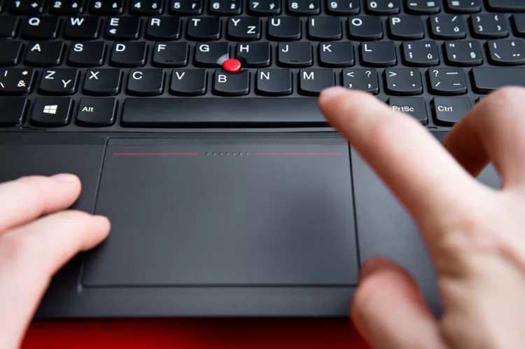 Female hands above the keyboard of a laptop with a red button 